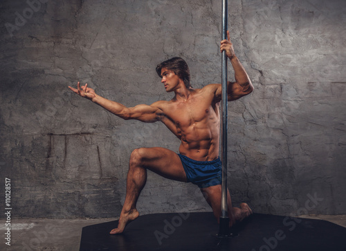 Shirtless man pole dancing.