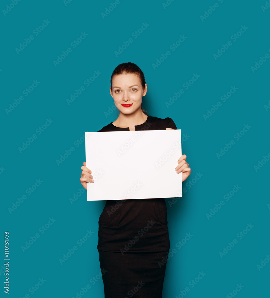 Colour studio portrait of pretty smiling girl showing empty blank board. Blue background isolated Colour studio portrait of pretty smiling girl showing empty blank board. Blue background isolated