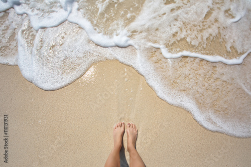 Vacation on ocean beach, feet on sea sand