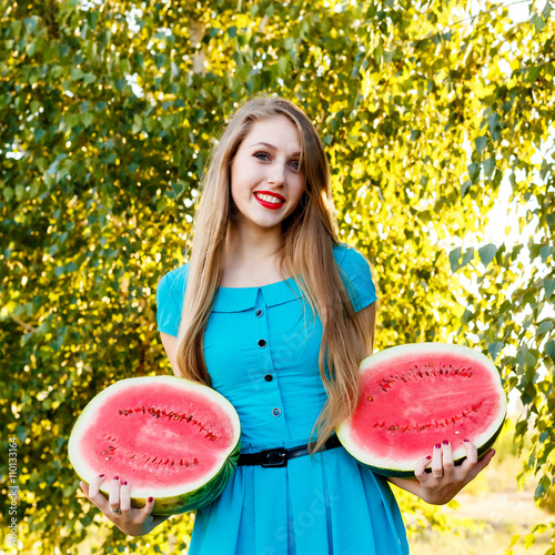 Beautiful blonde girl holding two halves of a sliced watermelon photo