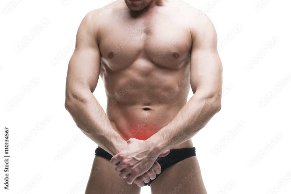 Man with pain in the prostate. Muscular male body. Handsome bodybuilder posing in studio. Isolated on white background with red dot