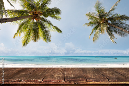 Fototapeta Naklejka Na Ścianę i Meble -  Old wood table with blurred sea and coconut tree background - Empty ready for your product display montage. Concept of beach in summer