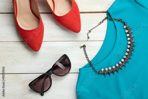 red womens shoes and t-shirt with a necklace and sunglasses on wooden background