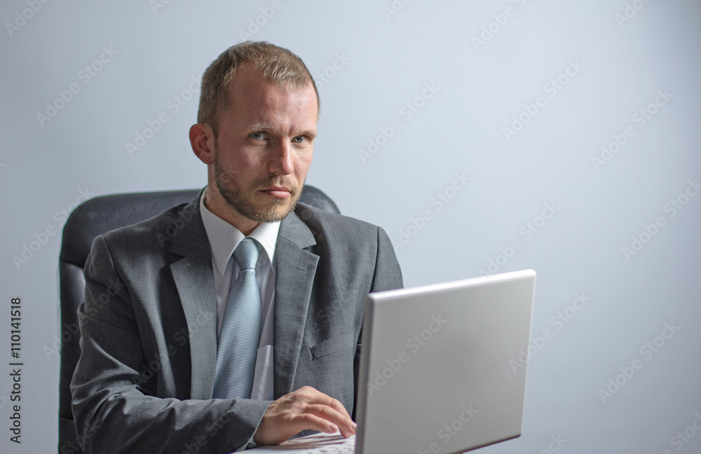 Chef im Anzug schaut skeptisch von Laptop auf Chef im Anzug schaut skeptisch von Laptop auf