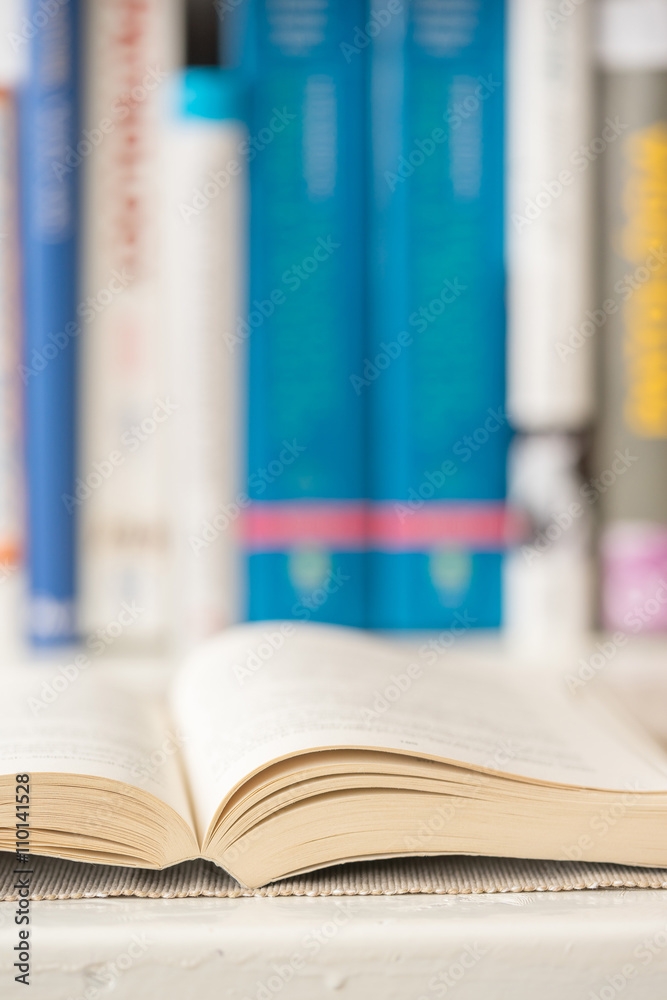Fototapeta premium Detail view of open book in library. Selective focus. Vertical shot.