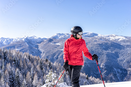 Female skier enjoys view on italien slopes with beautiful mountains in distance. Portrait shot.