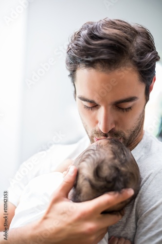 Father kissing baby while standing