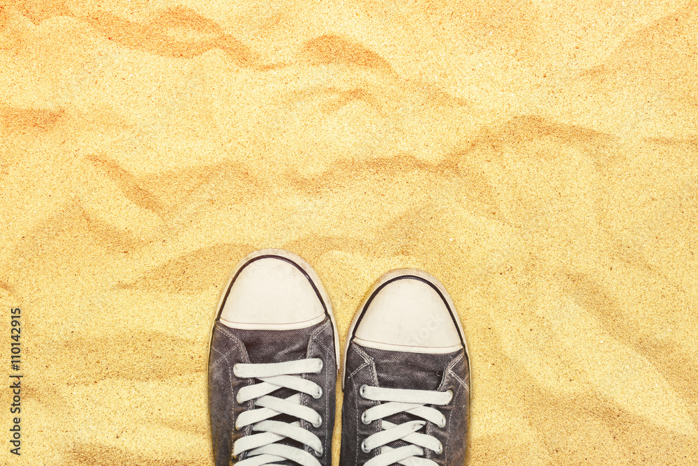Naklejka premium Feet in sneakers standing on war desert sand