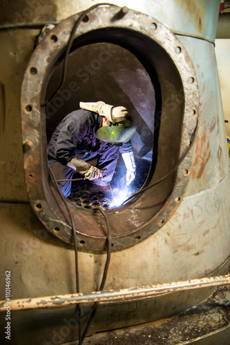 Welder at work at the boiler shipbuilding Co2 in ship repair yard on