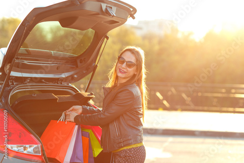 Caucasian woman putting her shopping bags into the car trunk © vladstar