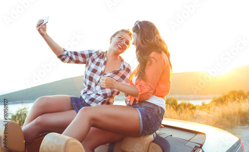 Two young beautiful girls are doing a photo of yourself in a cab © vladstar