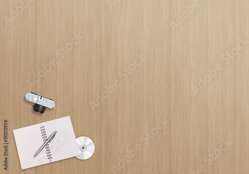 Office business desk top view with notebook, pen, compact disc and camera. Wooden background