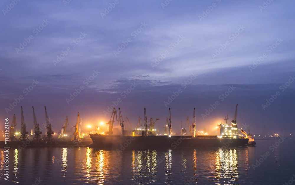 cargo ship in the port near the pier, night loading