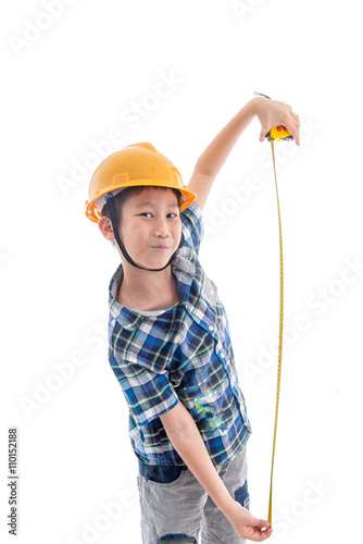 Asian boy dressed like worker holding measuring tape on white.