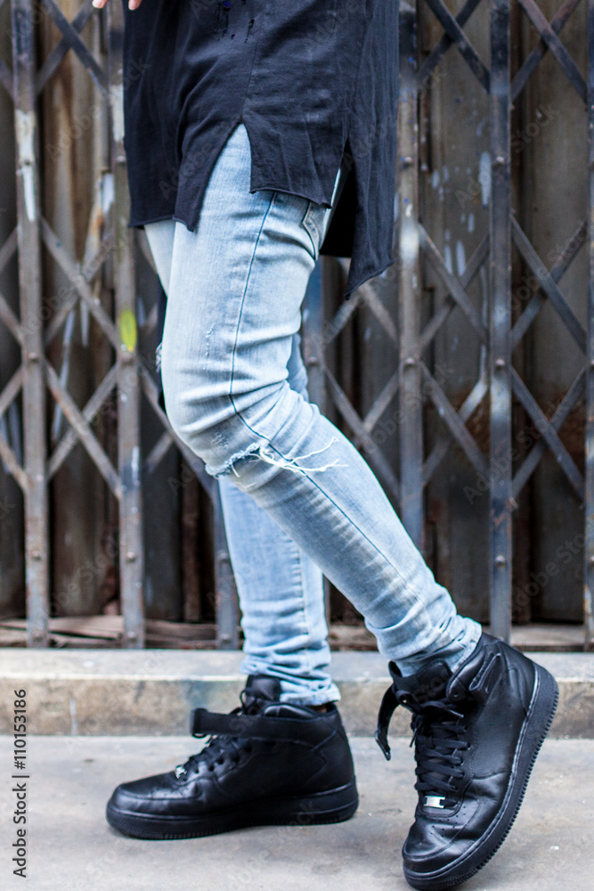 Young fashion man's legs in jeans on the street 