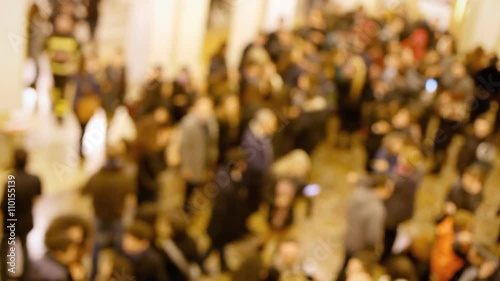 A flow of blurred people moving in a hall before or after a concert.