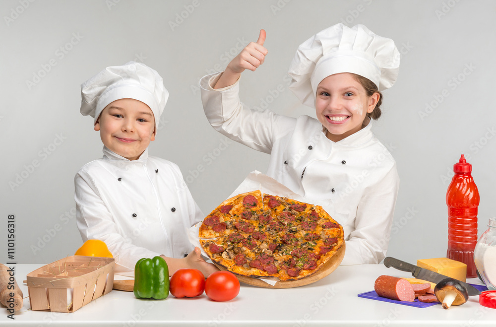 boy and girl in white uniform by the table with pizza boy and girl in white uniform by the table with pizza