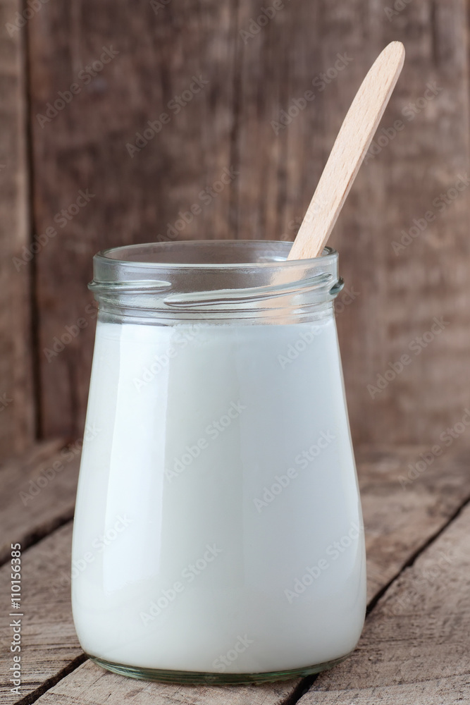 yogurt in glass jar with spoon on wooden background yogurt in glass jar with spoon on wooden background