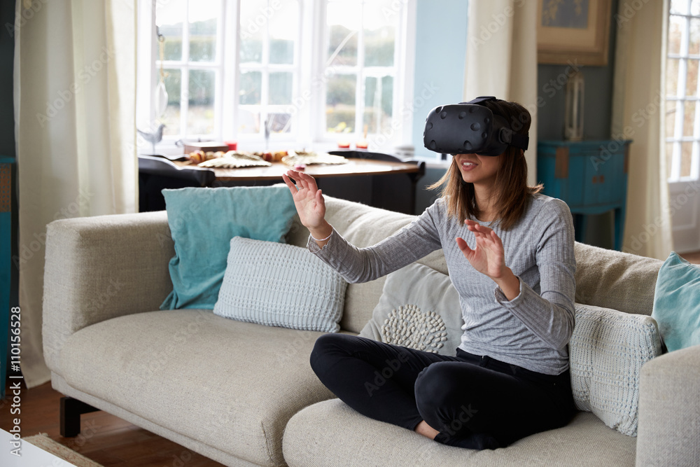 Obraz premium Woman Sits On Sofa At Home Wearing Virtual Reality Headset