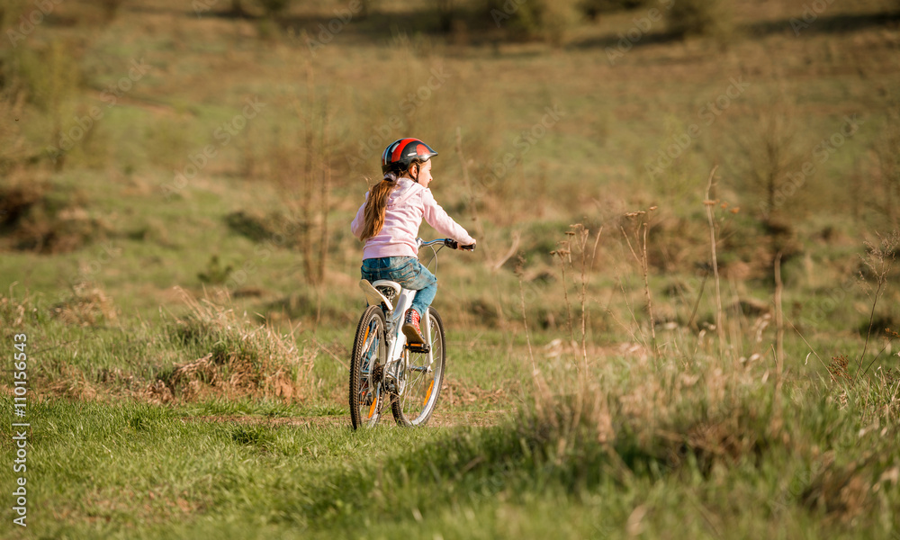 smiling little girl riding a bike turned away smiling little girl riding a bike turned away