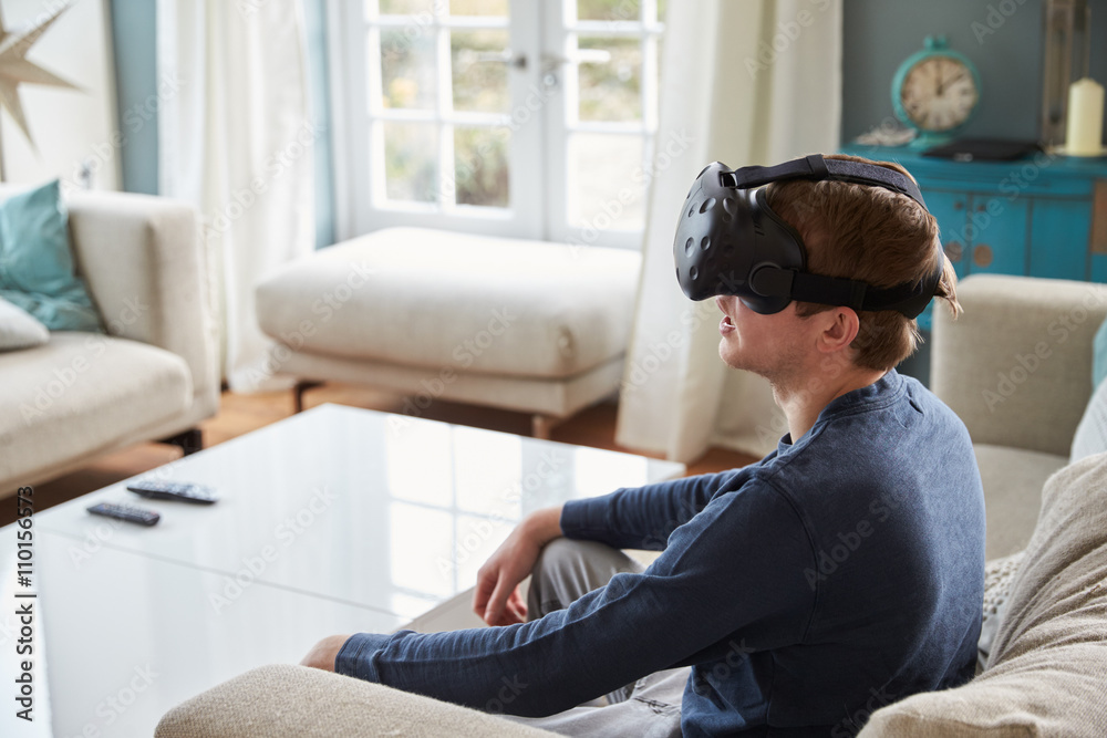 Obraz premium Man Sitting On Sofa At Home Wearing Virtual Reality Headset