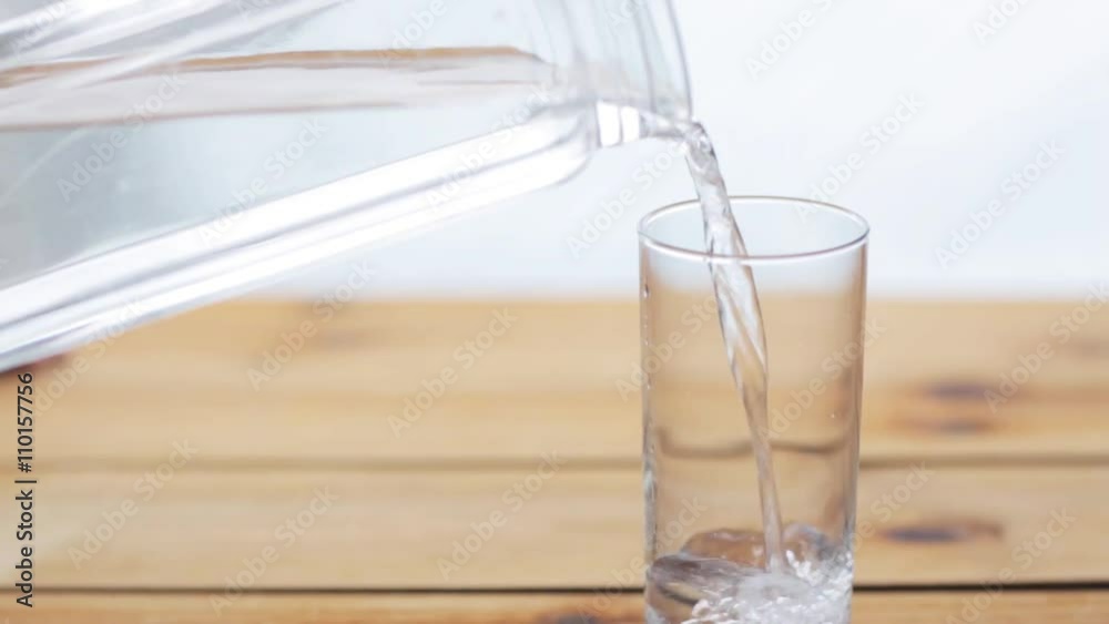 water pouring into glass on wooden table water pouring into glass on wooden table