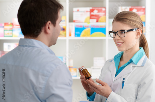Young medical salesperson showing pharmaceuticals to male client in drug store. Health care and medicine.  