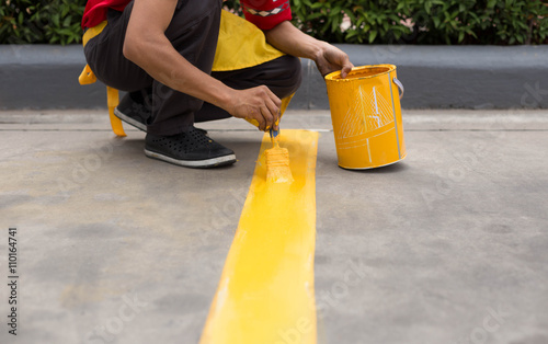 Man painting the yellow line on the concrete floor photo