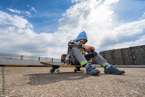 Boy sitting on skateboard and thinking about something © upslim