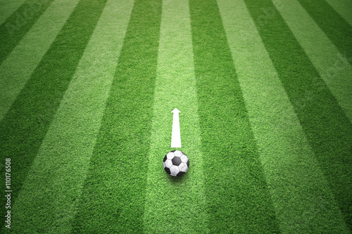 Sunny green football field with soccer ball and white arrow copy space background. Conceptual soccer play background with place for text. 