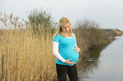 lifestyle capture of beautiful pregnant woman walks outdoor.