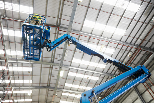 Photos Low angle view of a cherry picker being used in a warehouse