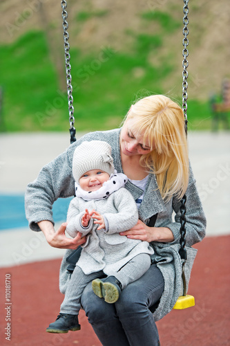 Mother and the little daughter shake on a swing.