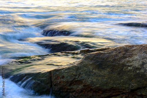 Sea water moving between the rocks during sunset