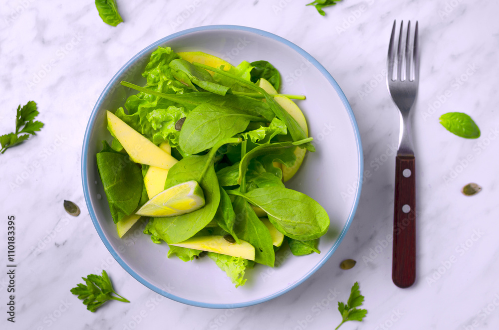 Spinach salad with fruit on marble with fork Spinach salad with fruit on marble with fork