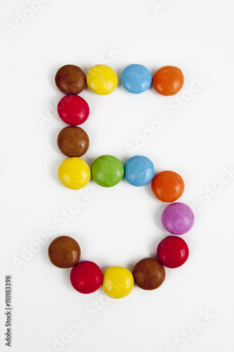 Il numero 5 formato da coloratissimi confetti di cioccolata.