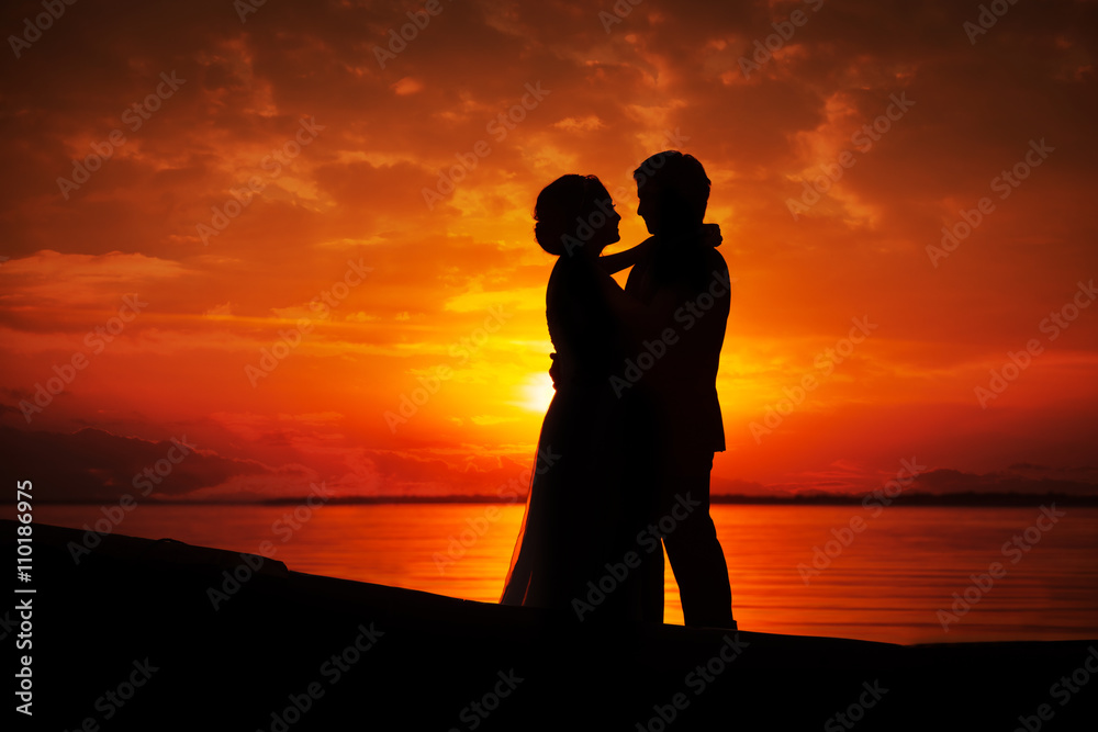 Silhouette of couple kissing in sunset