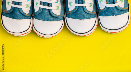 Baby sneakers on yellow background