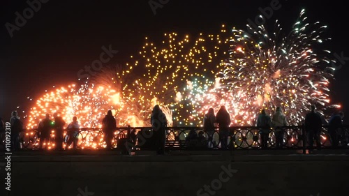 people standing on a bridge watching fireworks