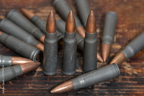 Bullets of 7.62 mm caliber. Kalashnikov machine gun on the wooden background.