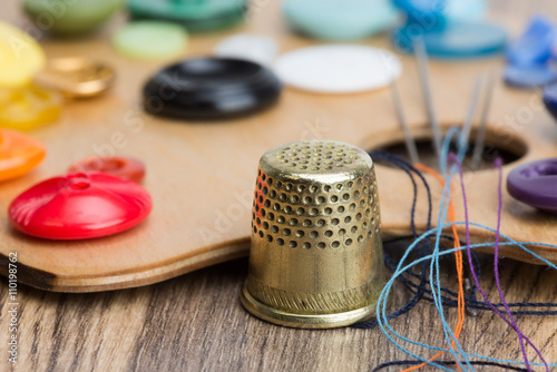 buttons, thimble, needle and thread on the palette
