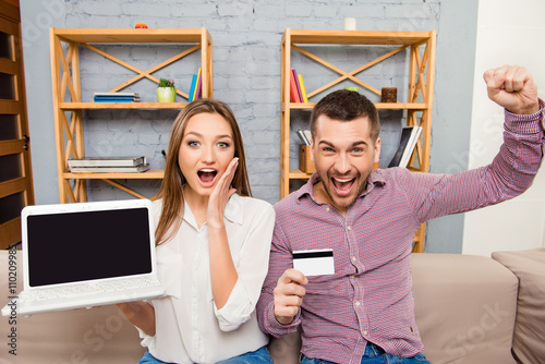 Happy man and woman screaming with laptop and bank card photo