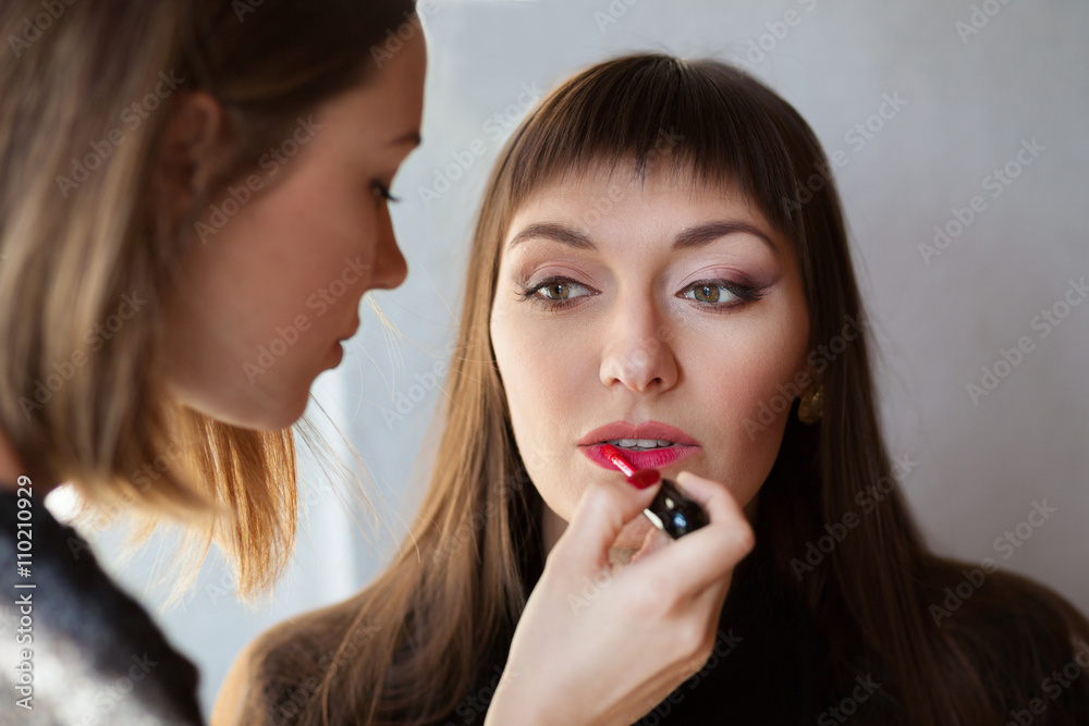 Make-up artist applying lipstick with brush on model lips Make-up artist applying lipstick with brush on model lips
