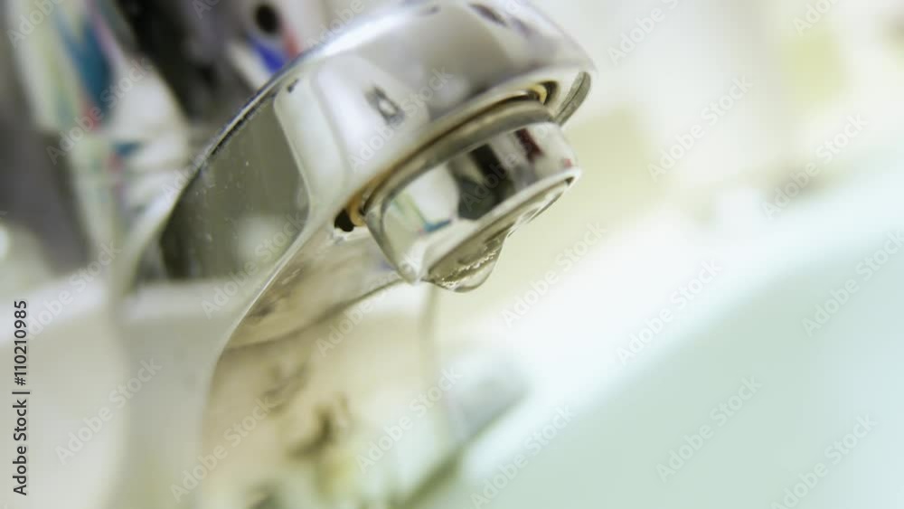 Water dripping from the tap faucet. Closeup macro shot showing the drops up close. Water dripping from the tap faucet. Closeup macro shot showing the drops up close.