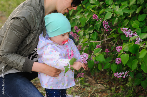 Happy mother and daughter in the garden of blooming lilacs