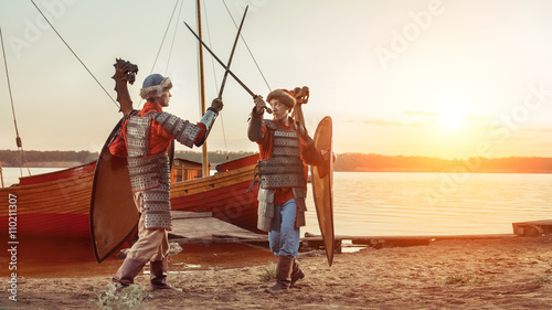 Battle of two medieval knights with swords and shields. Warships on the background.