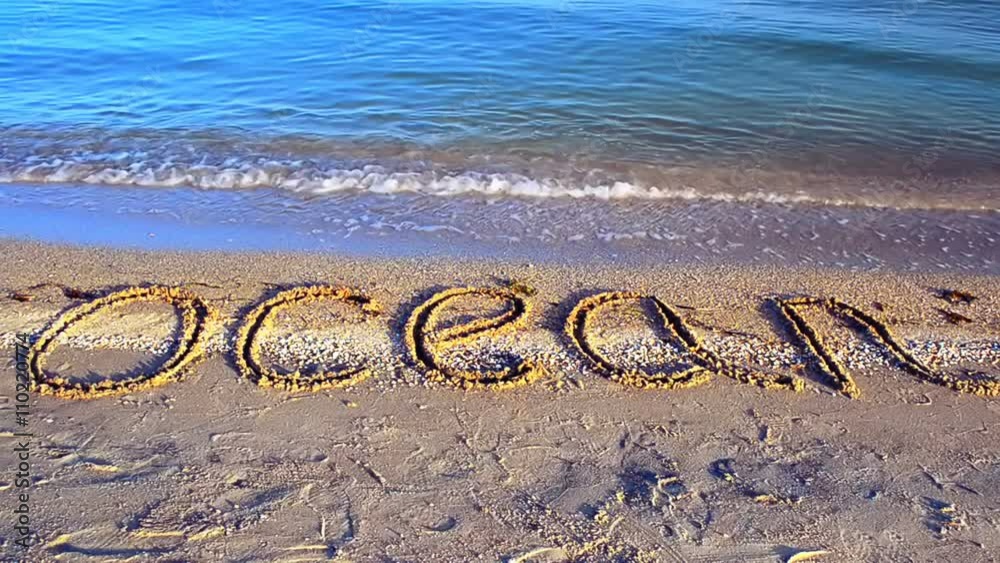 Inscription the ocean on the beach on sand.