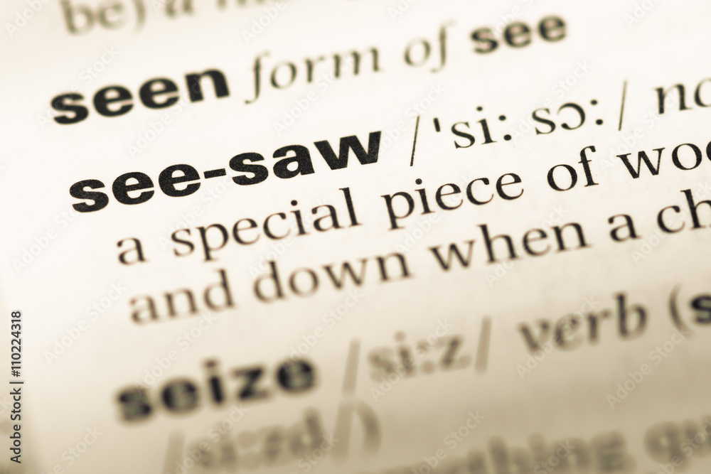 Close up of old English dictionary page with word see saw Close up of old English dictionary page with word see saw