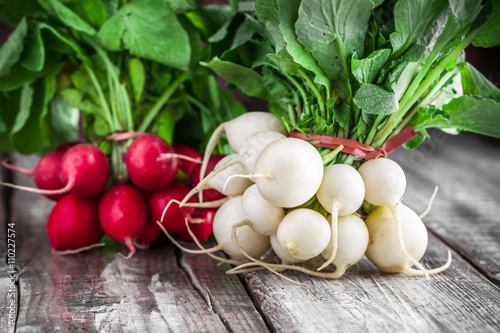 Red and white radish group close up on old rustic white wooden table with drops of water