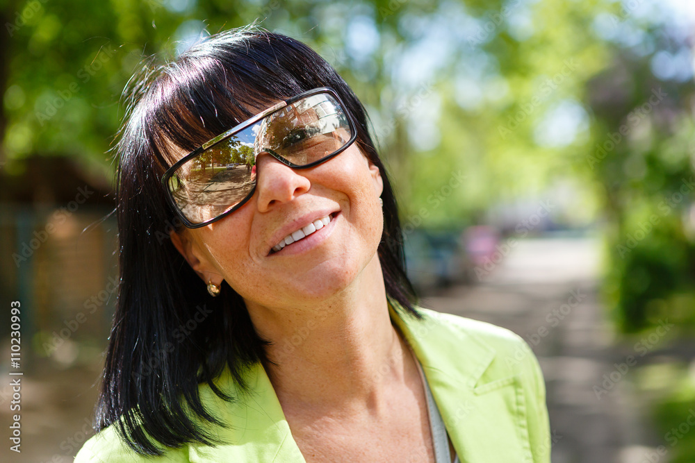 Close-up portrait of cute woman with white smile and sun glasses in outdoor. Happy Lady Dressed in a green jacket and have spring-summer mood Close-up portrait of cute woman with white smile and sun glasses in outdoor. Happy Lady Dressed in a green jacket and have spring-summer mood